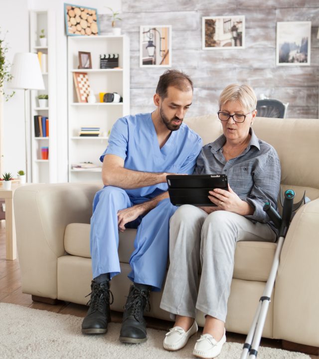 young doctor in nursing home helping senior woman